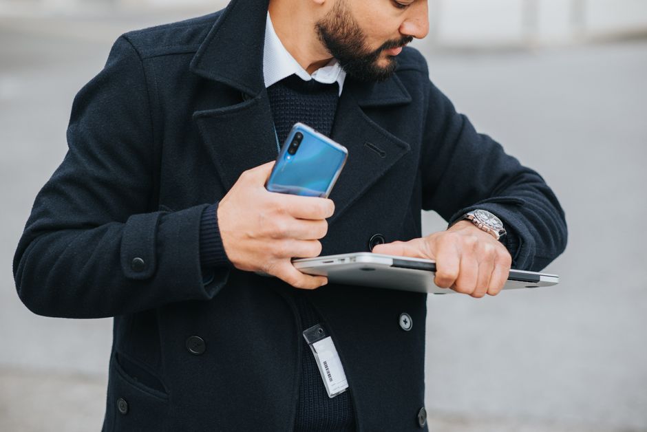 Osoba w domu sprawdza telefon przy laptopie i kluczach przed wizytą.