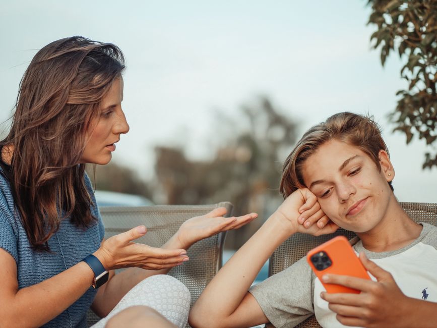 Rodzic i nastolatek spokojnie rozmawiają przy stole, patrząc na mapę w telefonie.