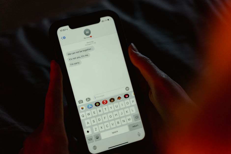 Osoba ostrożnie sprawdza nieoczekiwaną wiadomość na telefonie w biurowym korytarzu.