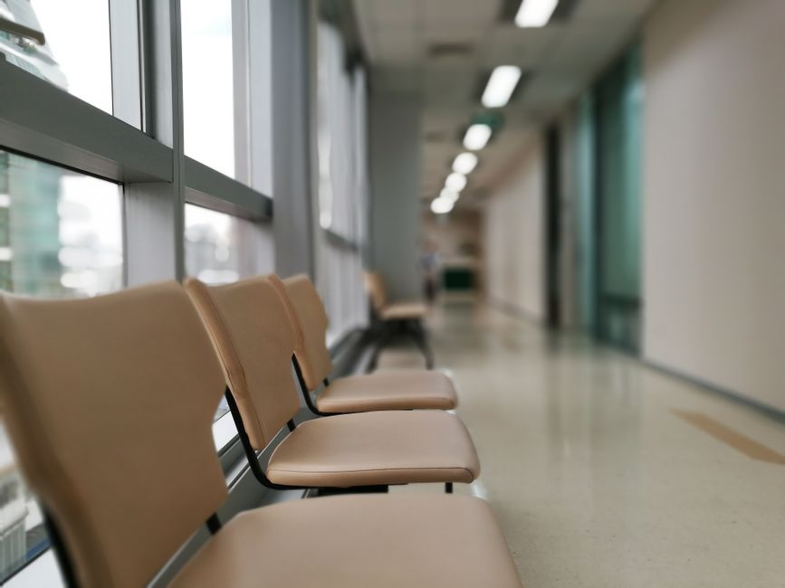 Wieczorem przed wejściem do powiatowego centrum zdrowia idzie kobieta z teczką, a w oknach świeci się światło.
