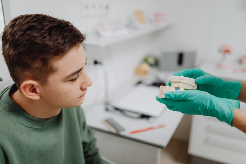 Dentysta omawia z pacjentem protezę zębową w gabinecie stomatologicznym.