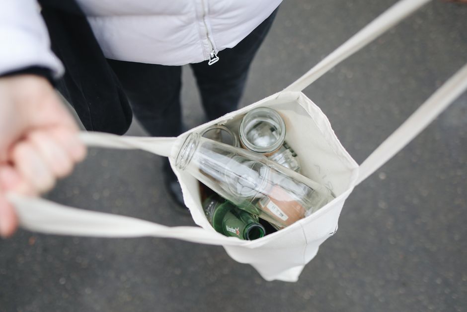 Podejrzana butelka z widocznym fragmentem szkła zabezpieczona w przezroczystym pojemniku na blacie.