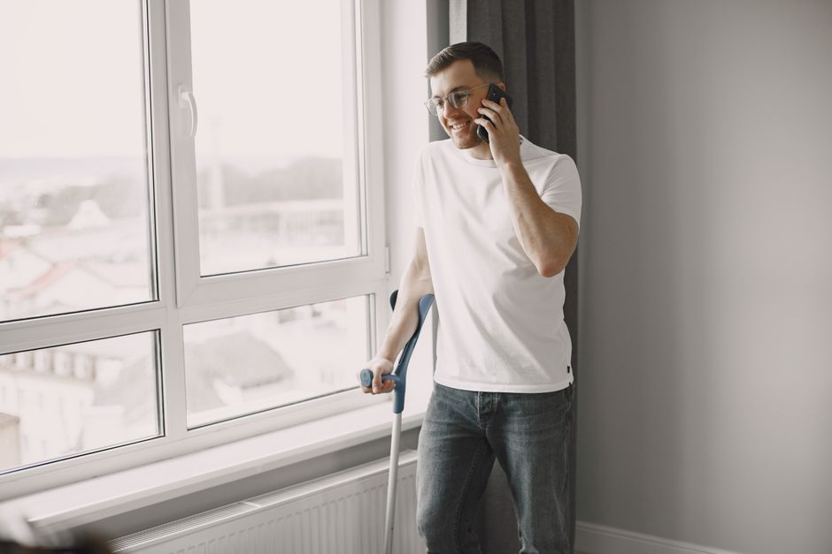 Osoba w jasnym pokoju fotografuje smartfonem przedramię na jednolitym jasnym tle, przy świetle dziennym.