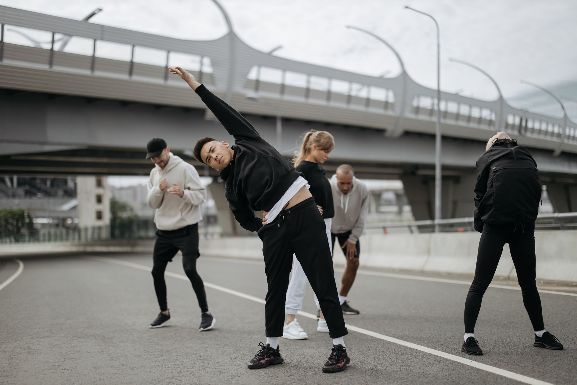 Grupa ludzi ćwiczy na świeżym powietrzu w parku — jogging, joga i jazda na rowerze.