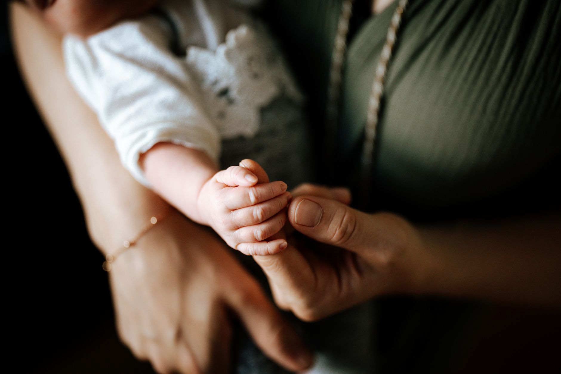 Mama trzymająca dziecko na kanapie, zamyślona, w przytulnym salonie
