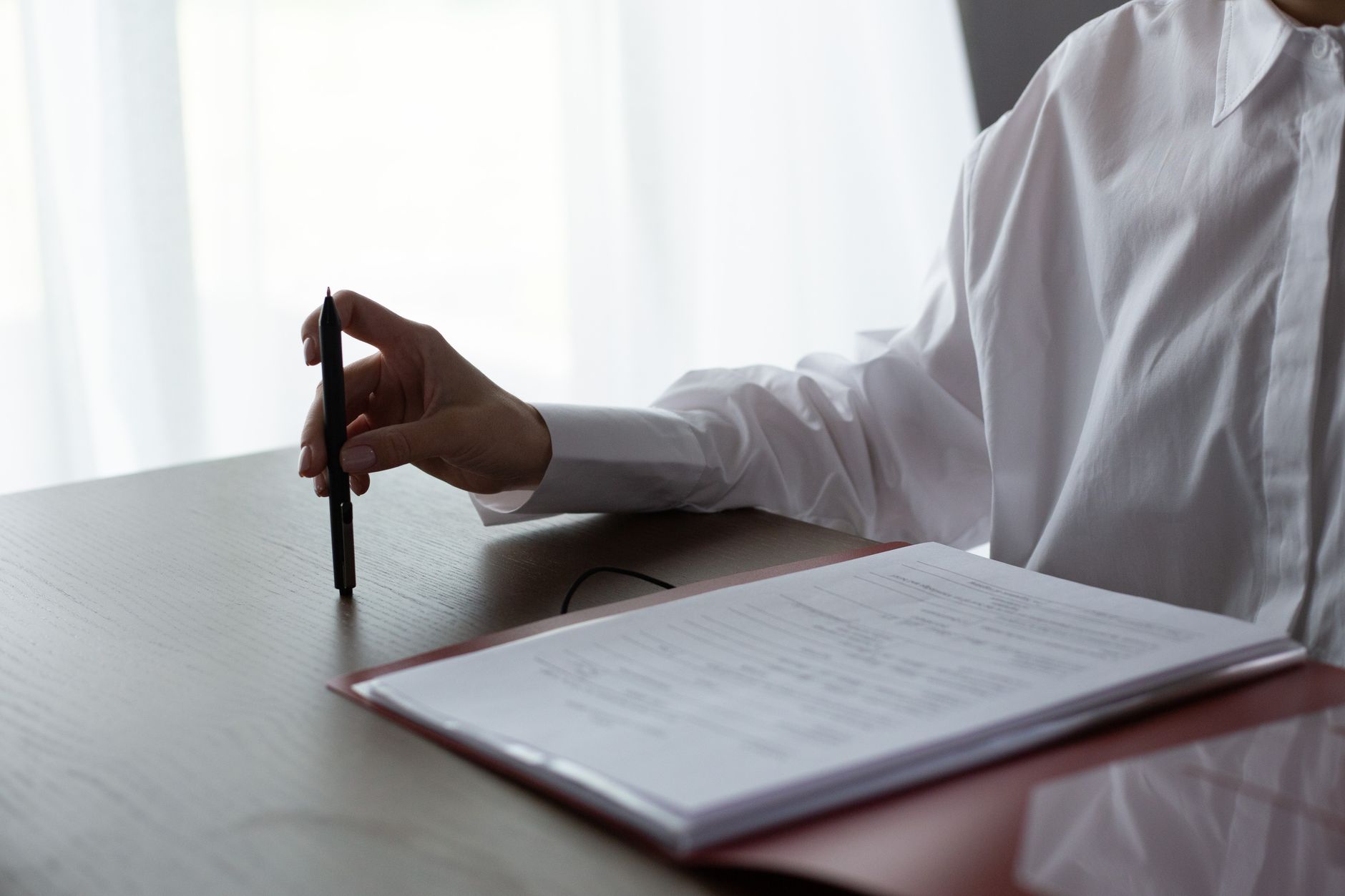 Kobieta sprawdza na laptopie informacje o klinice in vitro i przegląda dokumenty dotyczące dofinansowania