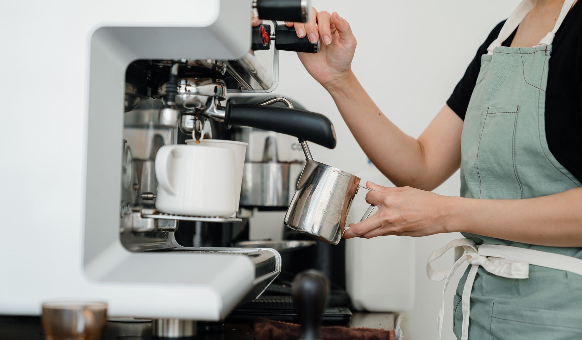 Barista przygotowujący kawę w przytulnej kawiarni, ludzie pijący napoje.