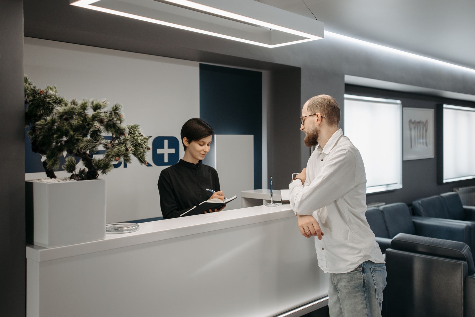 Recepcja w placówce medycznej, pacjent wypełnia formularze przed wizytą