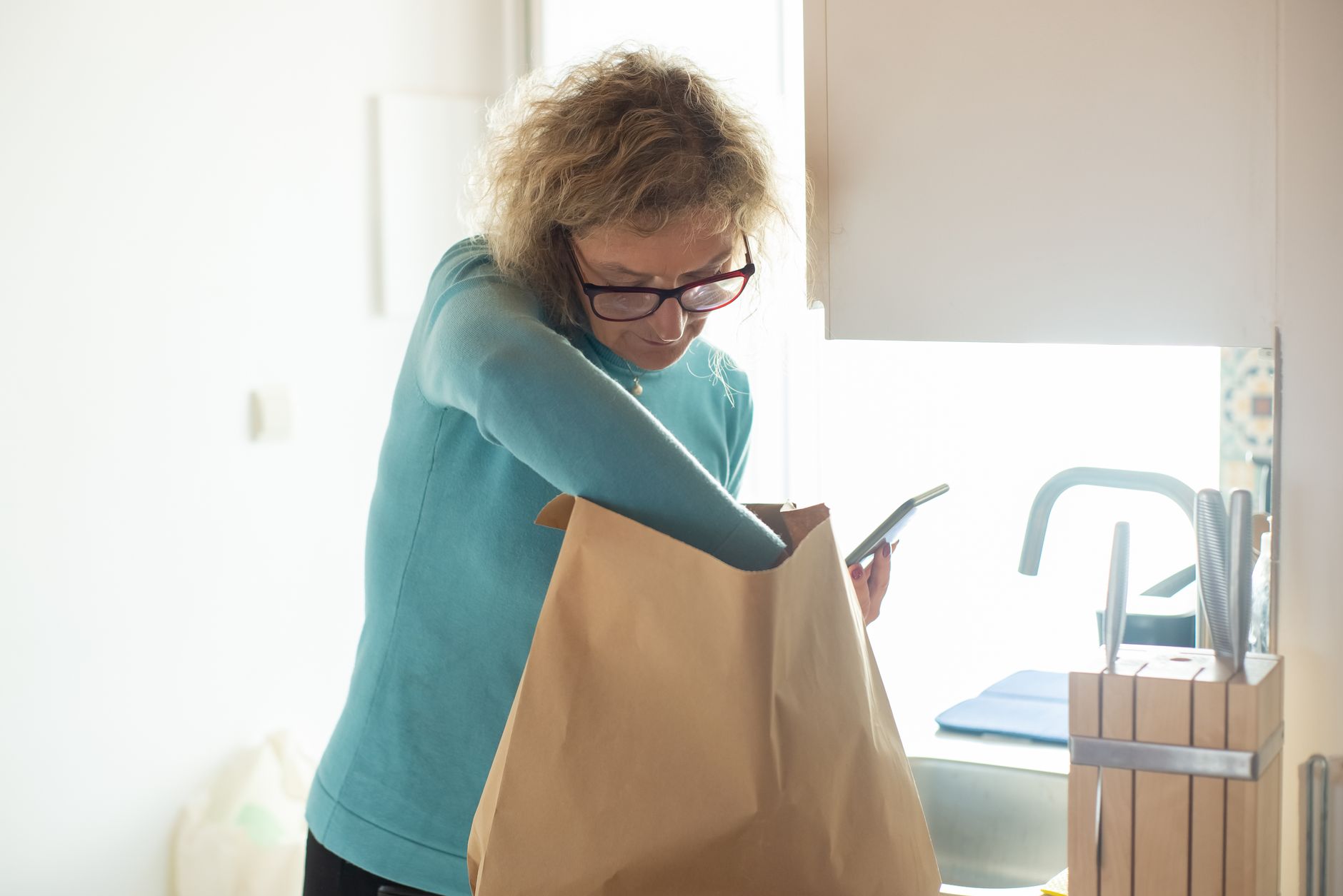 Osoba pakuje torbę przy drzwiach: okulary, etui i dokumenty przed wyjściem na wizytę